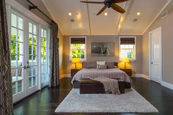 Primary bedroom with vaulted ceiling, ceiling fan, and French doors to a balcony