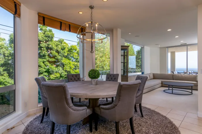 Open dining and living area with a round table, pendant light, and ocean-view windows