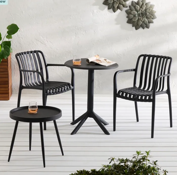 Black outdoor bistro table and slatted chairs staged on a patio