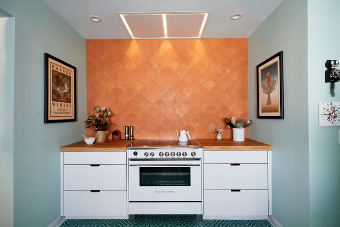 Kitchen with a scalloped terracotta tile backsplash, butcher block counters, and a Fisher & Paykel range